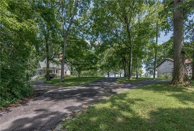 The blacktop drive winds through the tree line that shields the house from the street and forms a circle parking area for guests.