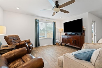 Living room with ceiling fan and light hardwood / 