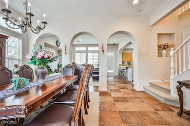 Dining area featuring arched walkways, light tile patterned floors, stairway, a chandelier, and recessed lighting