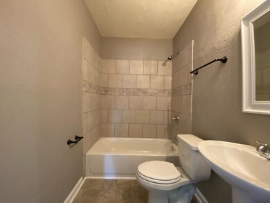 Full bathroom with a sink, toilet,  shower combination, and baseboards