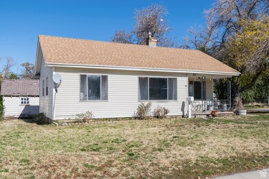 View of front of house featuring a porch, a front lawn, a chimney, and a shingled roof