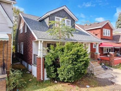 View of front facade with a shingled roof and brick siding
