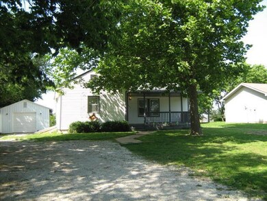 View of large shady driveway, front porch, and garage