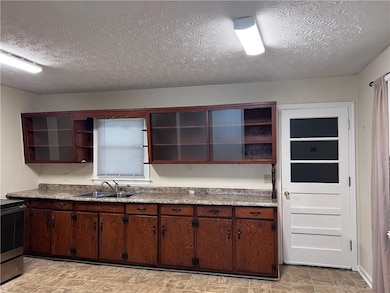 Kitchen with open shelves, a sink, stainless steel electric range, and a textured ceiling