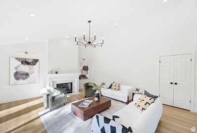 Living room featuring a premium fireplace, high vaulted ceiling, recessed lighting, light wood finished floors, and a chandelier