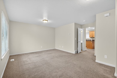 Empty room with light carpet and a textured ceiling