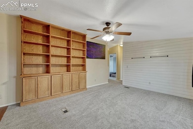 Unfurnished living room featuring lofted ceiling, light colored carpet,ceiling fan, built in bookshelves and brand new carpet.