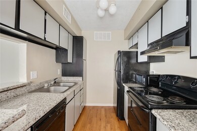 Kitchen featuring black appliances, light wood-sty