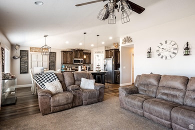 Living area with recessed lighting, ceiling fan, dark wood-style floors, vaulted ceiling, and a chandelier