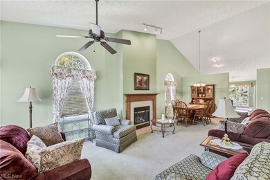 Living room with rail lighting, a textured ceiling, a fireplace, light carpet, vaulted ceiling, a high ceiling, and ceiling fan