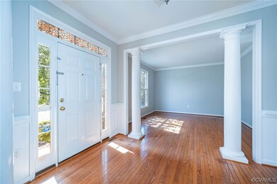 Hardwood floored foyer with ornate columns and orn
