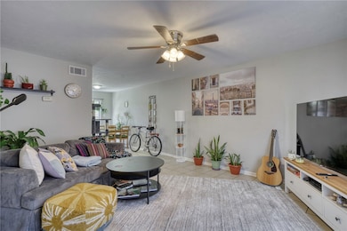 Tiled living room with ceiling fan and baseboards