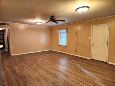 Spare room featuring ceiling fan, dark hardwood / wood-style flooring, crown molding, wood walls, and a textured ceiling
