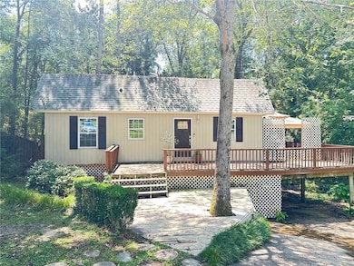 View of front facade featuring a deck, a patio area, a carport, and roof with shingles