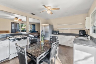 Kitchen with stainless steel appliances, ceiling fan, sink, white cabinets, and a center island