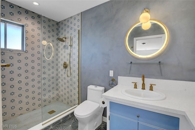Bathroom with vanity, toilet, and a stall shower