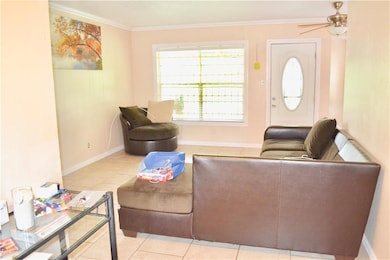 Living area with crown molding, light tile patterned floors, baseboards, and a ceiling fan