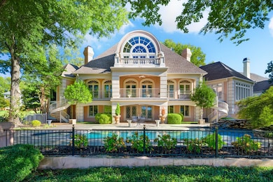 Back of house featuring french doors, a balcony, stairs, a patio, and a chimney