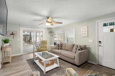Living room with ceiling fan, light wood-style flooring, and a textured ceiling