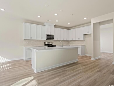 Kitchen with white cabinets, appliances with stain