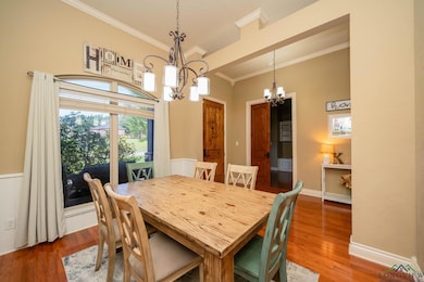 Dining area with a chandelier, wood finished floors, crown molding, and a towering ceiling