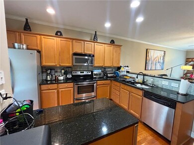 Kitchen with stainless steel appliances, a peninsula, ornamental molding, light wood-style flooring, and decorative backsplash
