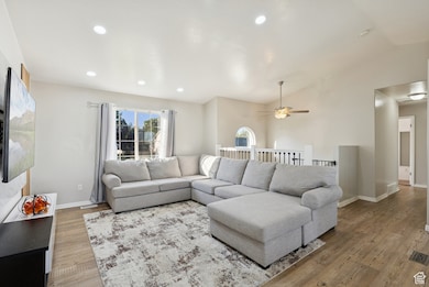 Living room featuring lofted ceiling, light wood-type flooring, and recessed lighting