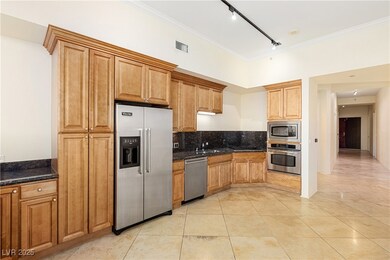 Kitchen with rail lighting, appliances with stainless steel finishes, backsplash, light tile patterned floors, and dark stone counters