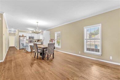 Dining area with a chandelier, light wood finished floors, ornamental molding, and baseboards