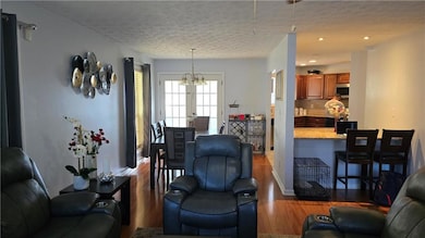 Living area featuring dark wood finished floors, a textured ceiling, a chandelier, and recessed lighting