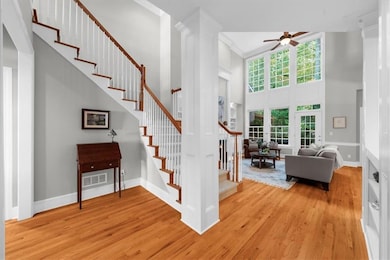 Stairs with wood finished floors, a towering ceiling, and a ceiling fan