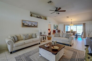 Tiled living room featuring ceiling fan and vaulte
