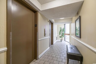Hallway with elevator, a textured ceiling, and lig
