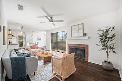 Living room with plenty of natural light, wood finished floors, a fireplace, and a ceiling fan
