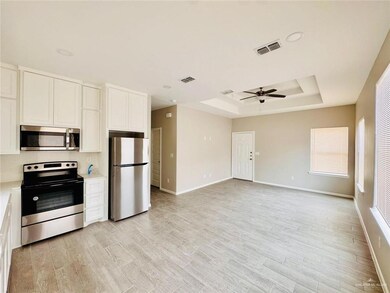 Kitchen featuring appliances with stainless steel finishes, a raised ceiling, ceiling fan, light countertops, and white cabinetry