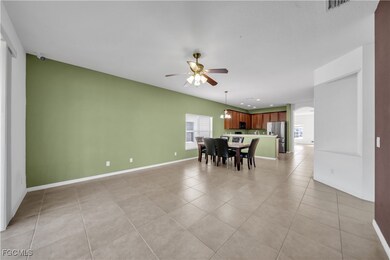 Dining room featuring light tile patterned floors, arched walkways, and a ceiling fan