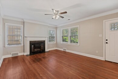 Unfurnished living room featuring crown molding, dark wood-style flooring, a fireplace, and ceiling fan