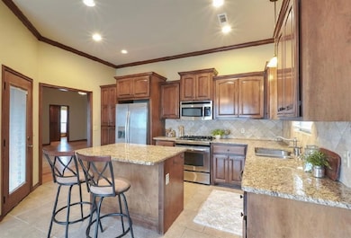 Kitchen with appliances with stainless steel finishes, ornamental molding, backsplash, a kitchen island, and sink