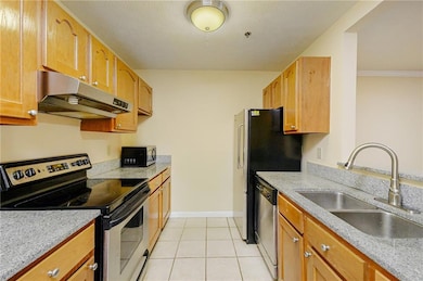 Kitchen featuring appliances with stainless steel finishes, under cabinet range hood, and light tile patterned floors