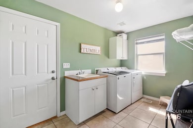 Laundry room featuring independent washer and dryer, cabinet space, and light tile patterned floors