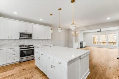 This custom kitchen showcases quartz counters, sleek stainless appliances, an enormous center island & an abundance of storage. The kitchen overlooks the dining & living rooms.