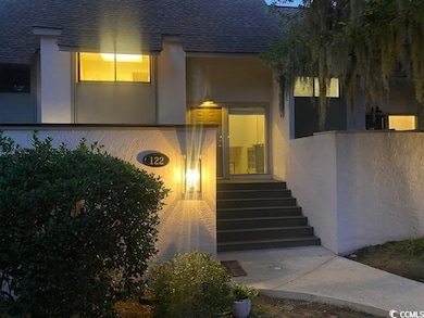Entrance to property with a shingled roof and stucco siding