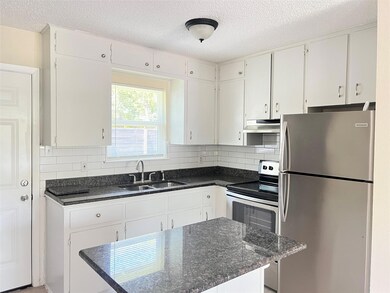 Kitchen featuring appliances with stainless steel finishes, a textured ceiling, white cabinetry, and dark stone counters