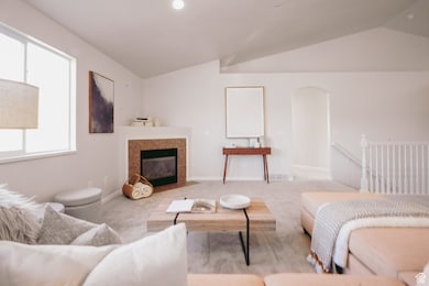 Carpeted living area featuring lofted ceiling, a fireplace, and arched walkways