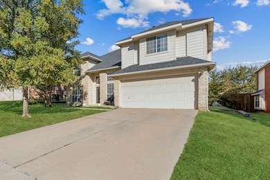 Traditional home with a shingled roof, a front lawn, an attached garage, driveway, and brick siding