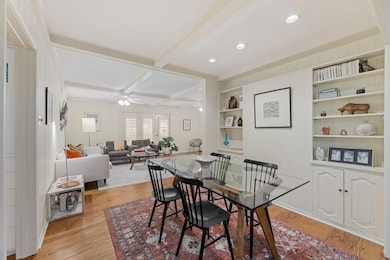 Dining space featuring beamed ceiling, light wood-style floors, built in shelves, ceiling fan, and coffered ceiling