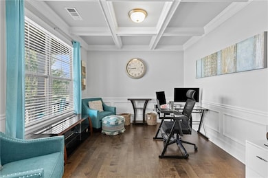 Office space with beam ceiling, coffered ceiling, ornamental molding, wood finished floors, and wainscoting