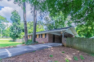 Ranch-style house featuring brick siding, asphalt driveway, and a carport
