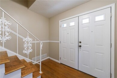 Foyer entrance with visible vents, stairs, baseboa