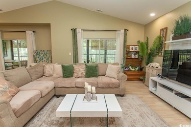 Living area with vaulted ceiling, wood finished floors, plenty of natural light, and recessed lighting